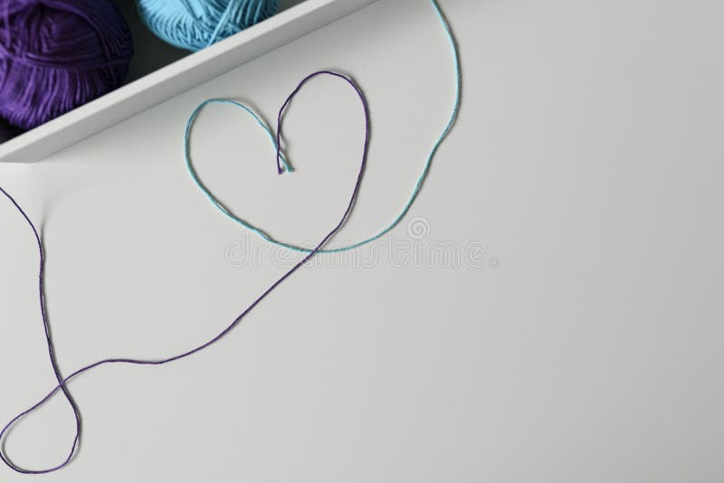 Knitting wools strands used to design colorful heart symbol on white background with copy space. Knitting wools strands used in a creative way to design stock photos