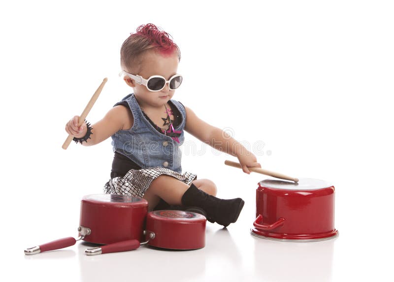 Little Drummer. Adorable toddler dressed as a rock star with a pink Mohawk and banging on pots and pans with drum sticks stock images