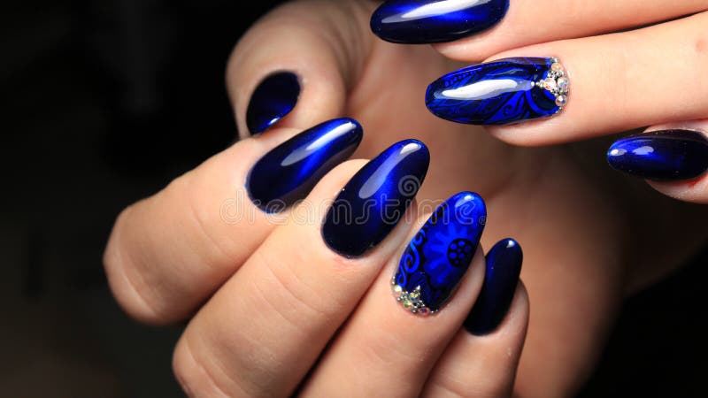 Manicure, cat`s-eye and blue stained glass gel polish with a picture and rhinestones royalty free stock photo