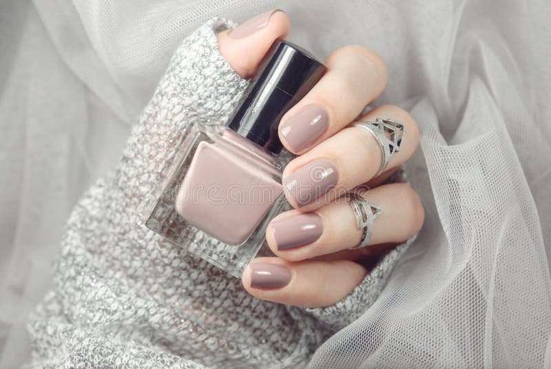 Manicure on female hands with nude nail polish stock photos
