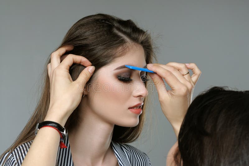 Master corrects the eyebrows of the model before shooting. stock image