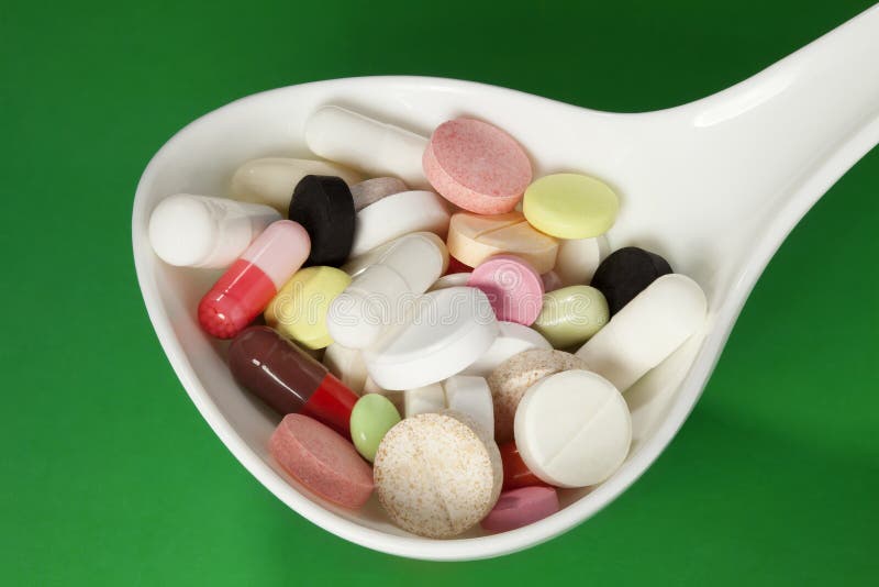 Multi colored pills in white spoon stock image