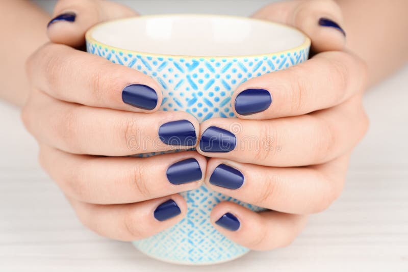 Nail art concept. Beautiful female hands with neat manicure holding cup royalty free stock photography