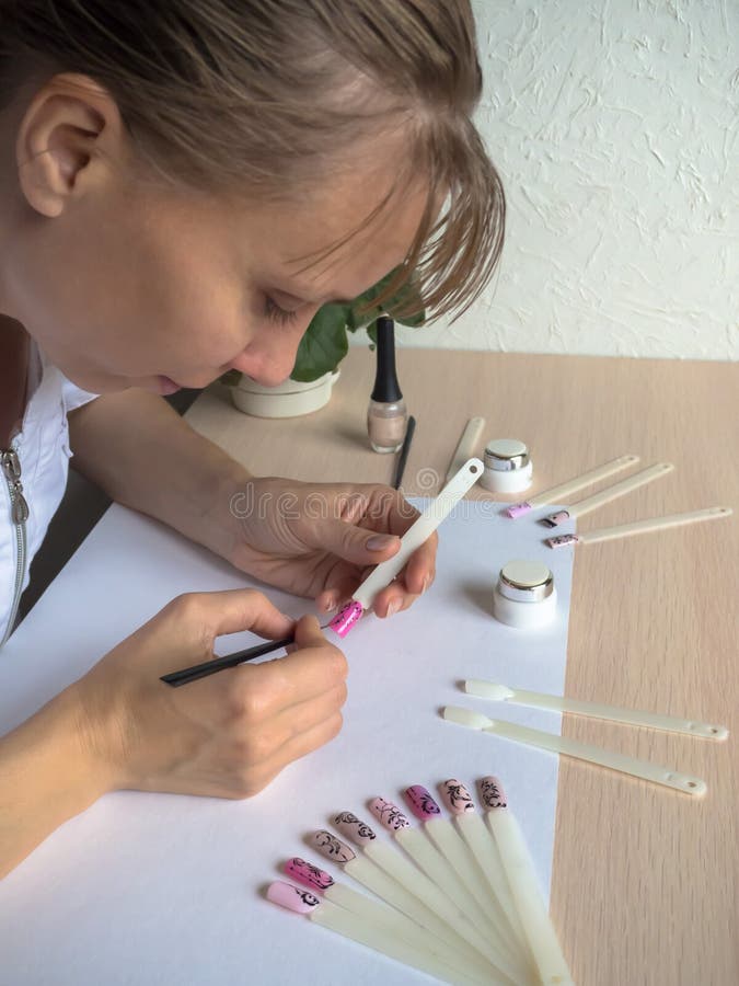 Nail art design. Female master draws on tips. stock photos