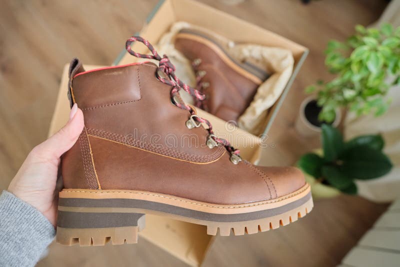 New womens leather brown waterproof winter boots in hands of female. New womens leather brown waterproof hiking winter autumn boots in hands of female, trendy royalty free stock images