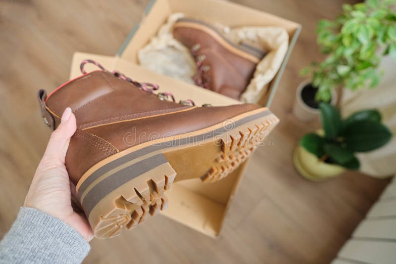 New womens leather brown waterproof winter boots in hands of female. New womens leather brown waterproof hiking winter autumn boots in hands of female, trendy royalty free stock image