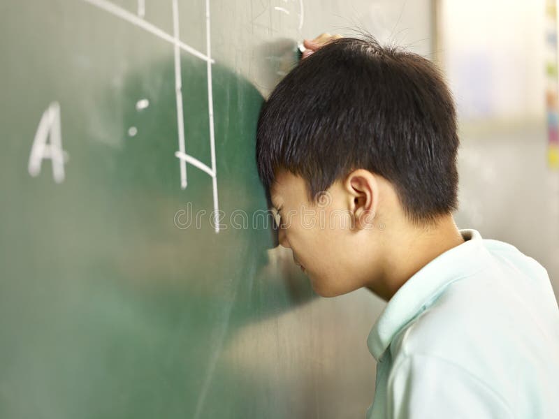 Painful asian pupil banging his head on the blackboard. Painful asian elementary schoolboy banging his head on blackboard while solving geometry problem royalty free stock images