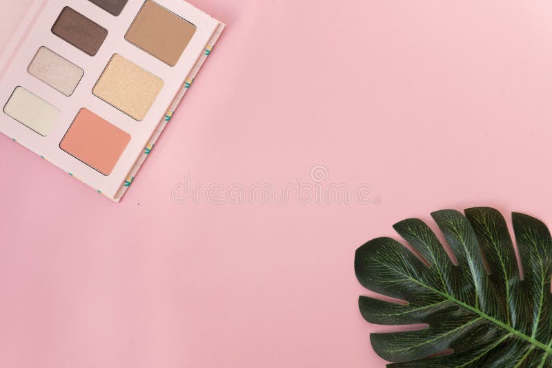 Palette of multicolor cosmetic make up with a monstera leaf on pink background. Pastel color palette, minimalism, light pink stock photography