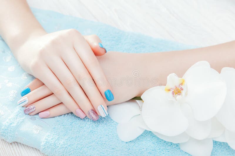 Pastel blue, pink and white manicure with orchid. Body care concept stock photography