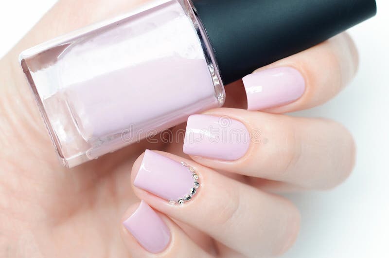 Delicate pastel pink manicure with rhinestones on white background stock photos