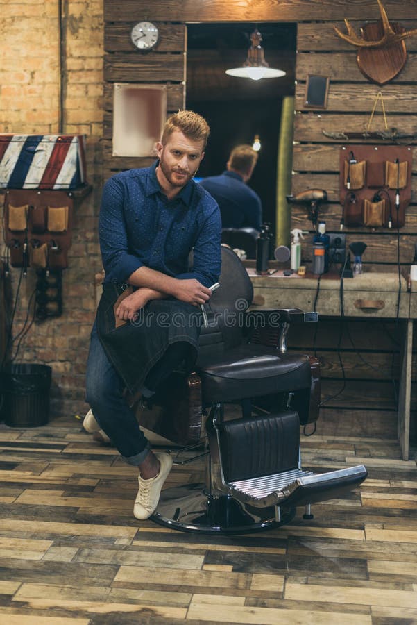 Portrait of handsome caucasian male barber with fashionable hairstyle. At barber shop stock photo