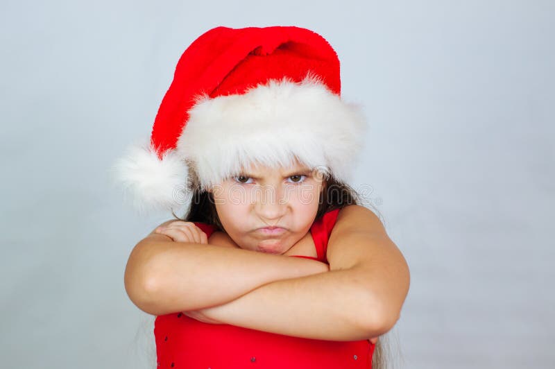 portrait of a little cute girl in a Christmas hat is very unhappy and angry royalty free stock photos