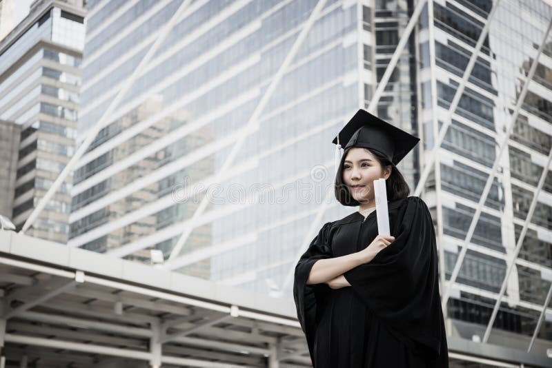 Portrait of young female graduates in square academic cap smiling happy holding diploma against stock photo