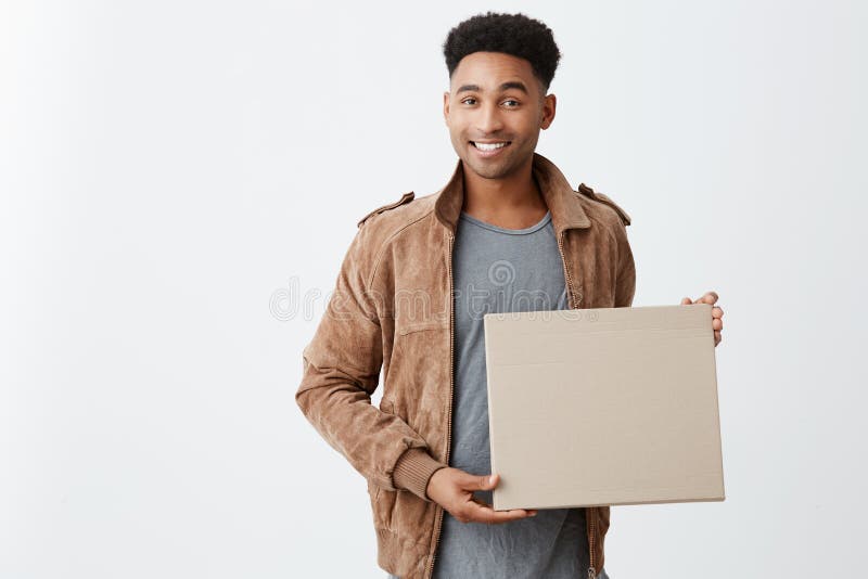 Positive emotions. Close up of young beautiful black-skinned male with afro hairstyle in casual stylish clothes holding. Cardboard in hands, looking in camera stock photos