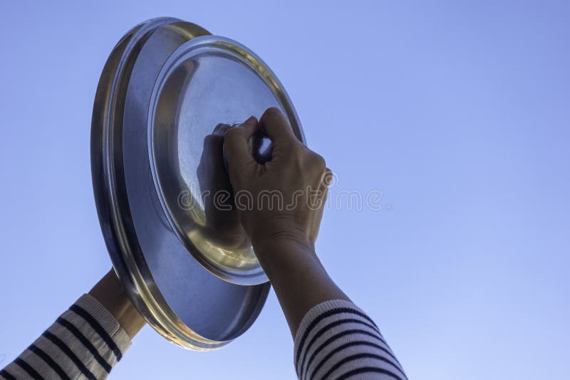 Protest against the government measures. Woman hands banging pot lids against blue sky. Banging pots and pans from the. Windows and balcony royalty free stock image