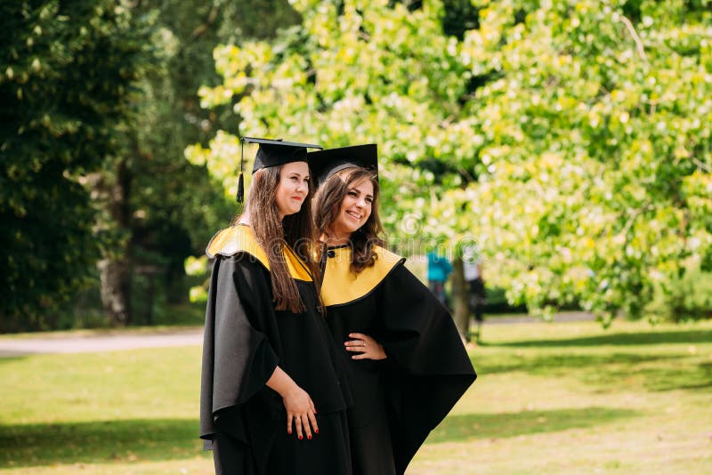 Riga, Latvia. Two young women graduates of the University of Latvia dressed in gown graduates and Square academic caps stock photo