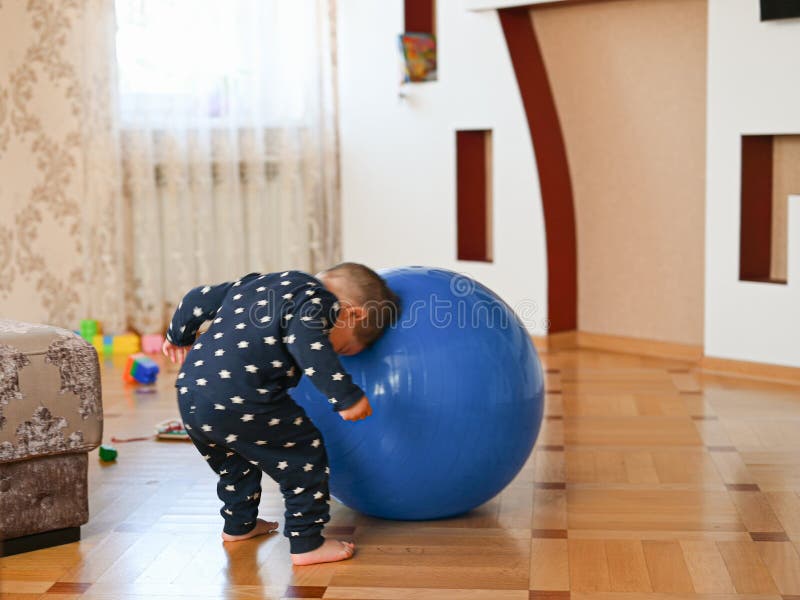 A small child is playing with a ball. Baby banging his head on a ball. High quality photo stock photography