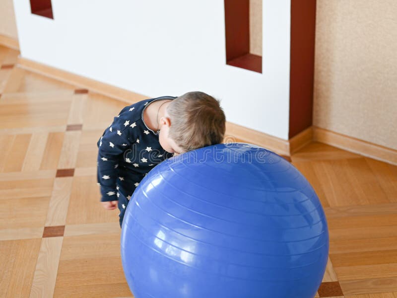 A small child is playing with a ball. Baby banging his head on a ball. High quality photo stock photography