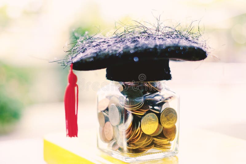 Square academic cap with the glass jar of coin on the book again stock photo
