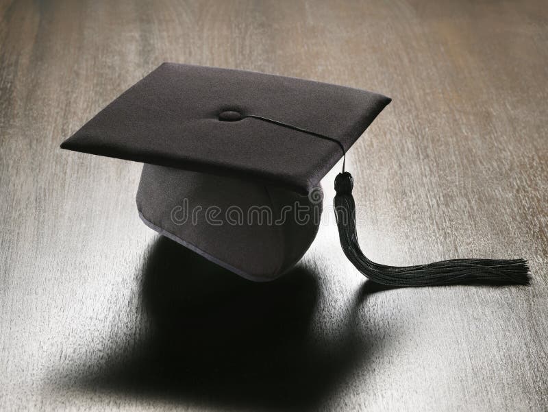 Square academic hat. Black square academic hat, or mortarboard, on wooden surface royalty free stock photography
