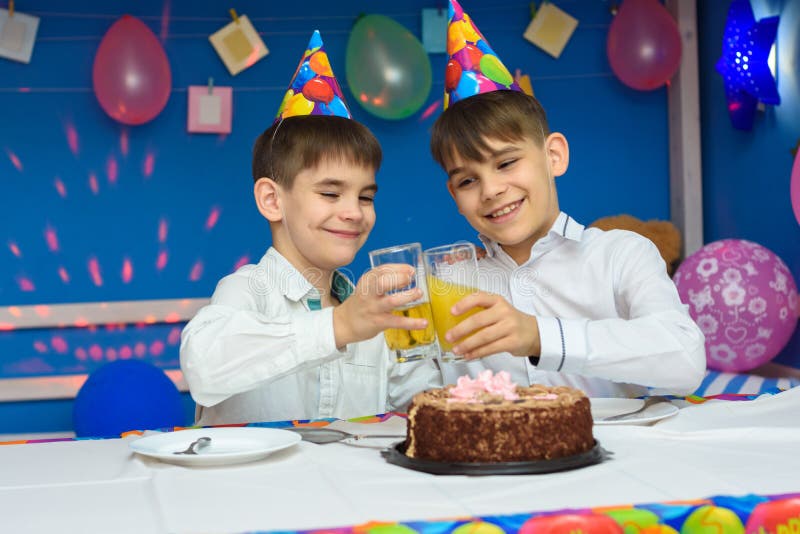 Two brothers banging glasses of juice at a birthday party. Two brothers banging glasses of juice at a birthday  party stock image