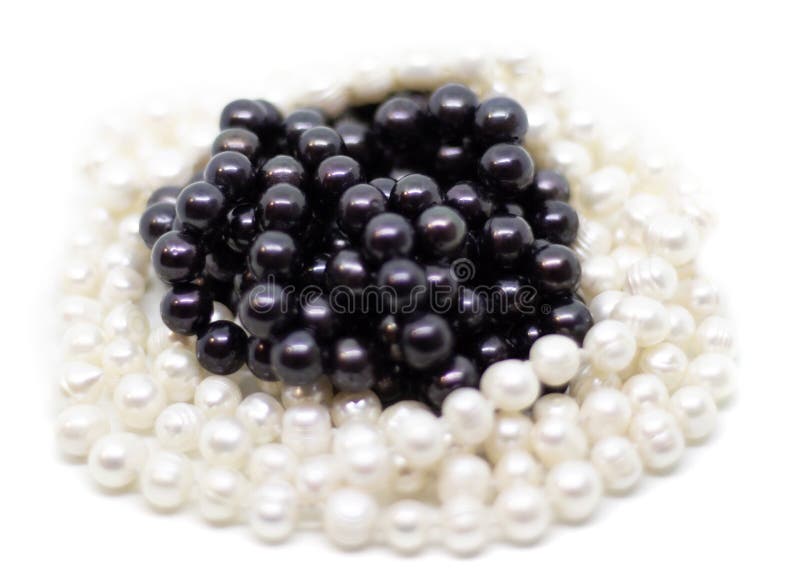 Two strands of white and black pearls on white background isolated. Two strands of white baroque and black pearls on white background isolated stock images