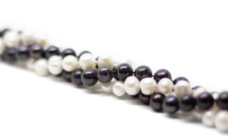 Two strands of white and black pearls intertwined on white background. Two strands of white baroque and black pearls intertwined on white background stock photos