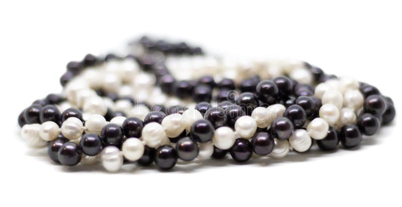 Two strands of white and black pearls intertwined on white background. Two strands of white baroque and black pearls intertwined on white background stock photography