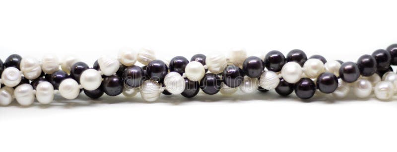 Two strands of white and black pearls intertwined on white background. Two strands of white baroque and black pearls intertwined on white background stock photography