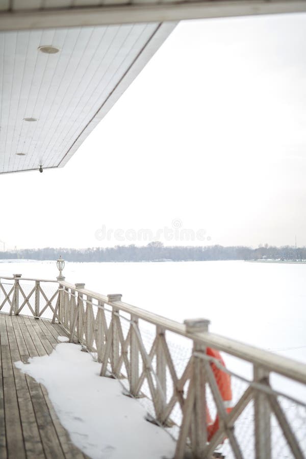 White snow on the wooden vintage open deck, old peeling paint light milky color, steel and copper lanterns hanging on the wall,. Snowy winter royalty free stock photography