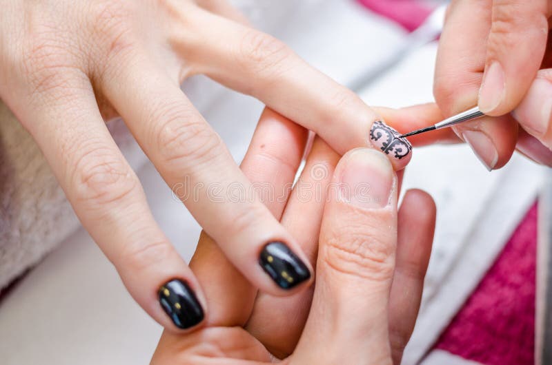 Woman applying black drawing nail polish stock photo