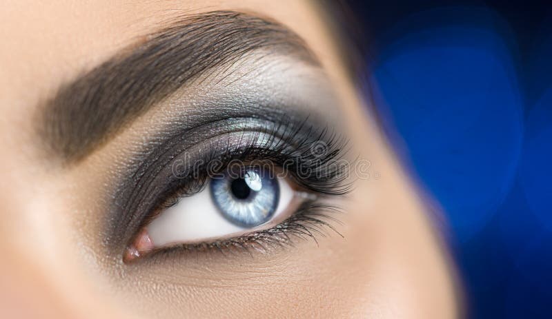 Woman blue eye with perfect makeup. Beautiful professional smokey eyes holiday make-up. Eyebrows shaping, eyes and eyelashes stock images