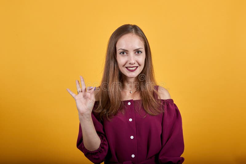 Woman in burgundy bluse over orange background showing sign okay with smile royalty free stock photos