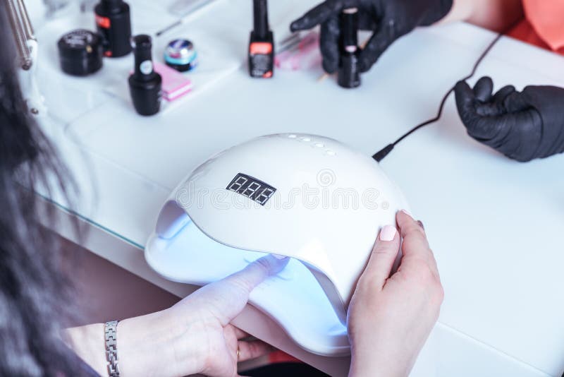 Woman drying her nail polish with uv lamp stock photography