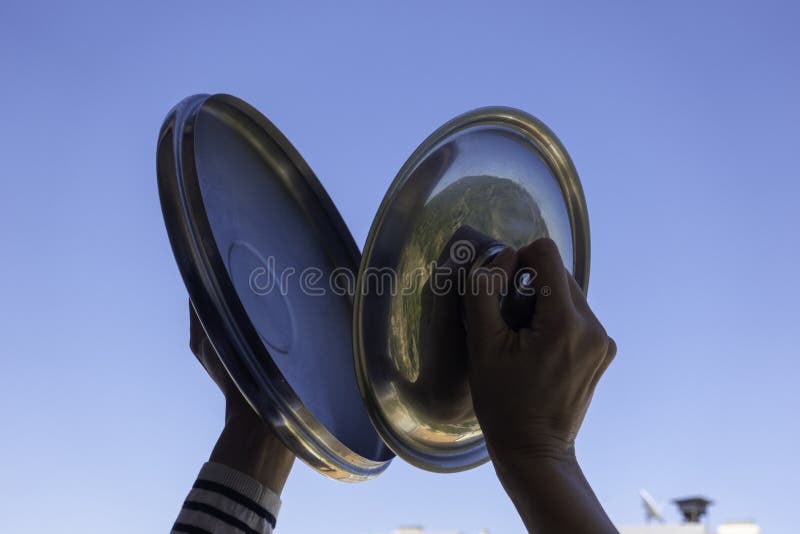 Woman hands banging pot lids against blue sky. Protest against the government measures. Banging pots and pans from the. Windows and balcony in Spain royalty free stock photography