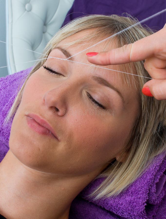 Woman having threading hair removal procedure. Attractive blond woman having threading hair removal procedure stock photography