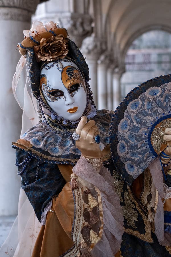 Woman poses in ornate, detailed costume, mask and hat, at the Doges Palace, St Mark`s Square during during Venice Carnival, Italy. Woman poses in ornate royalty free stock images