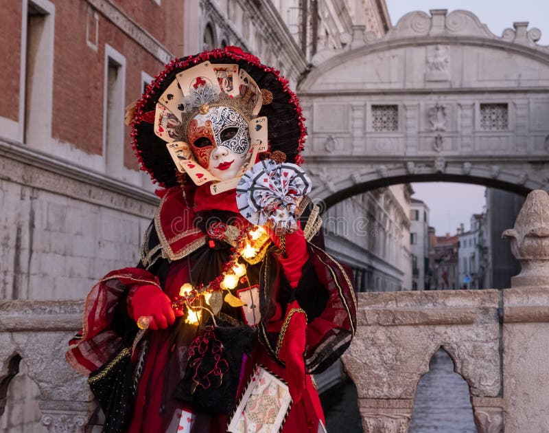 Woman poses in ornate, detailed costume, mask and hat in front of the Bridge of Sighs, St Mark`s Square  during Venice Carnival, I. Taly. Costume is made up of stock photography