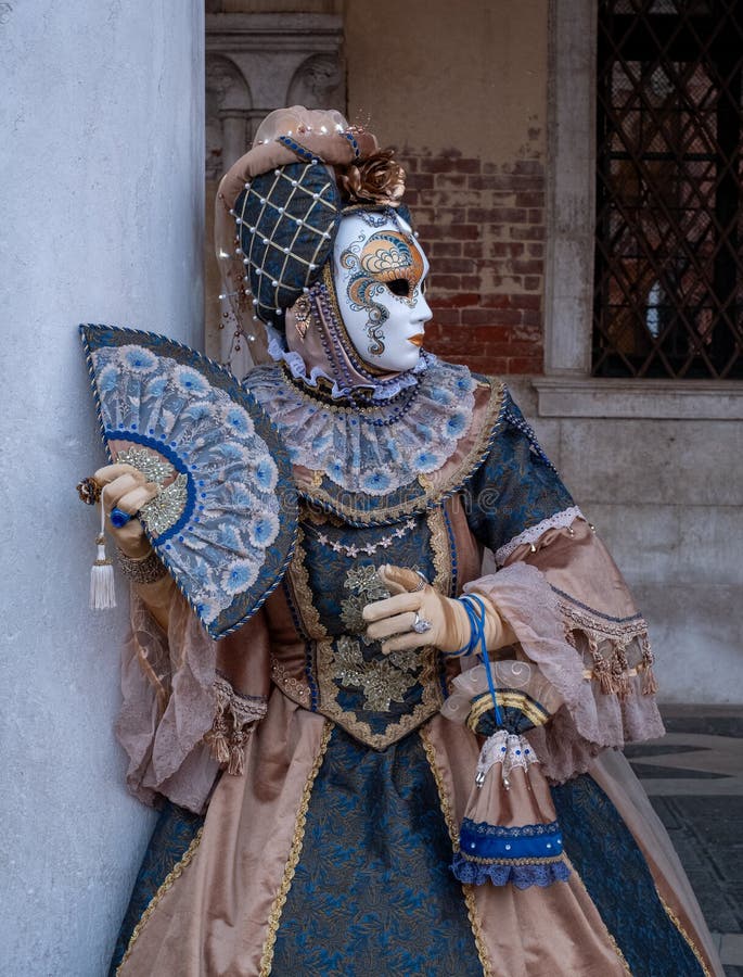 Woman poses in ornate, detailed costume, mask and hat, at the Doges Palace, St Mark`s Square during during Venice Carnival, Italy. Woman poses in ornate stock photography