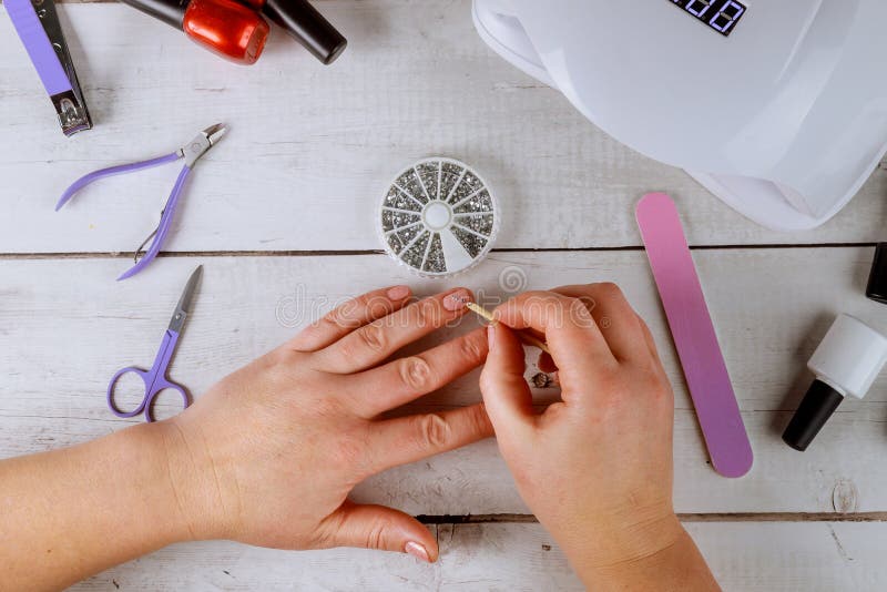 Woman puts rhinestones on nail. Making gel manicure stock photos