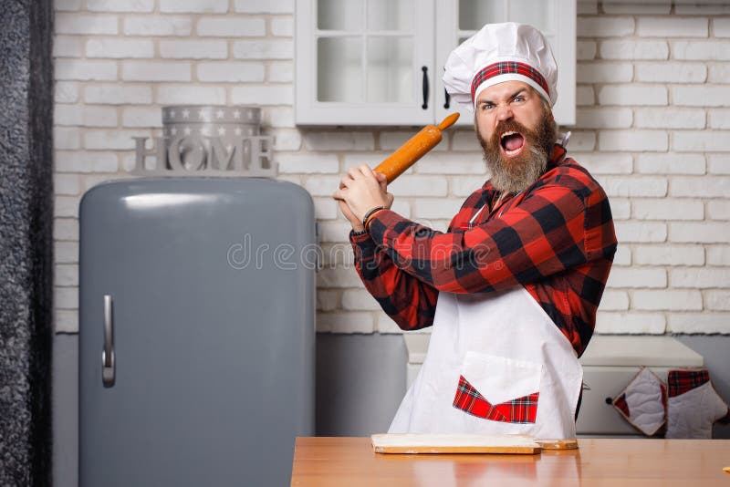 Young bearded chef angry or banging on someone on kitchen. Young bearded chef angry or banging on someone on kitchen royalty free stock photography
