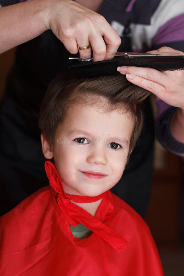 Young child with smile at the hairdresser having a haircut. Beautiful young child with smile at the hairdresser having a haircut stock photo