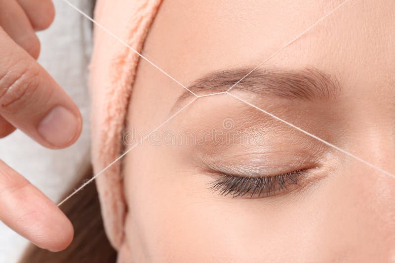 Young woman having eyebrow correction procedure. In beauty salon, closeup stock photo