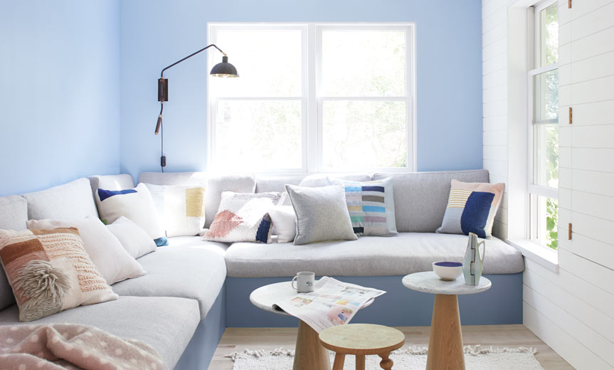 Light blue living room walls frame a large gray banquette Light blue living room walls frame a large gray banquette
