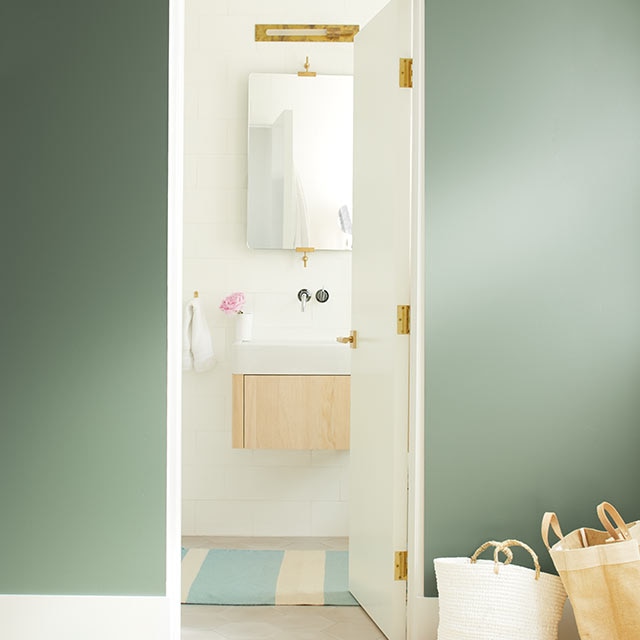 A dark green wall leads to a bright, neutral bathroom A dark green wall leads to a bright, neutral bathroom